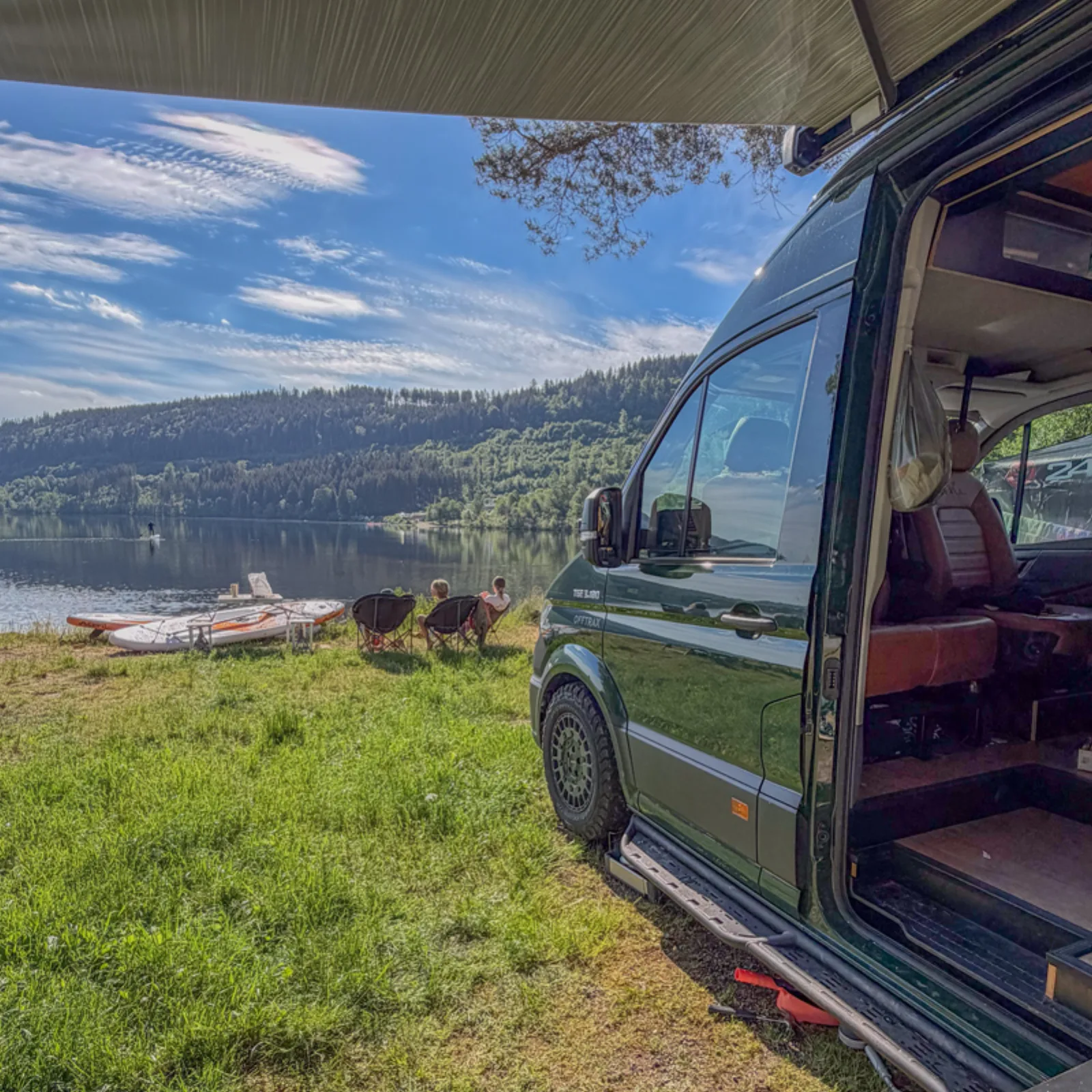 Campervan pitched beside Lake Titisee with paddleboards on the shore