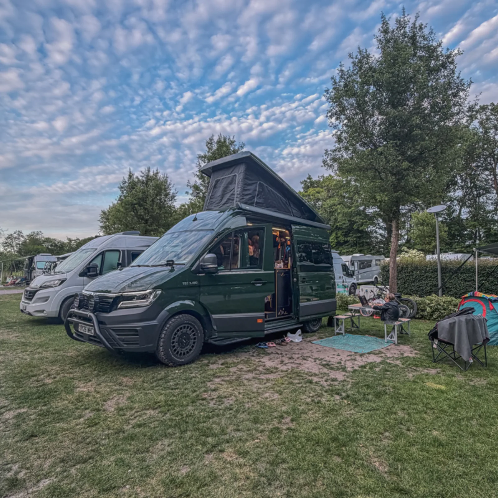Campervan with the pop-top up on a grassy pitch at Camping Memling