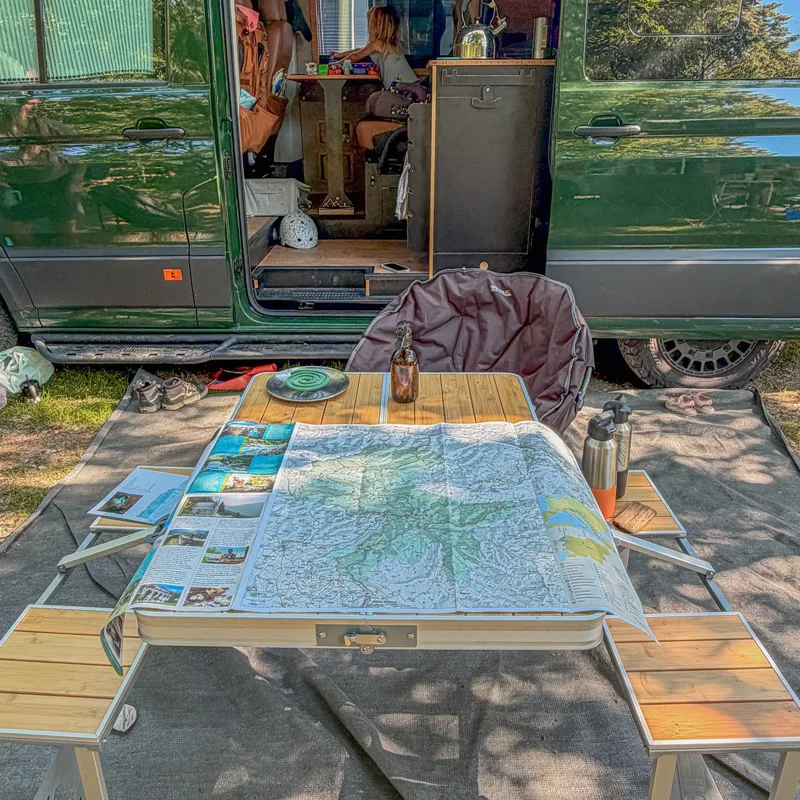 Map spread across a picnic table outside the Offtrax campervan